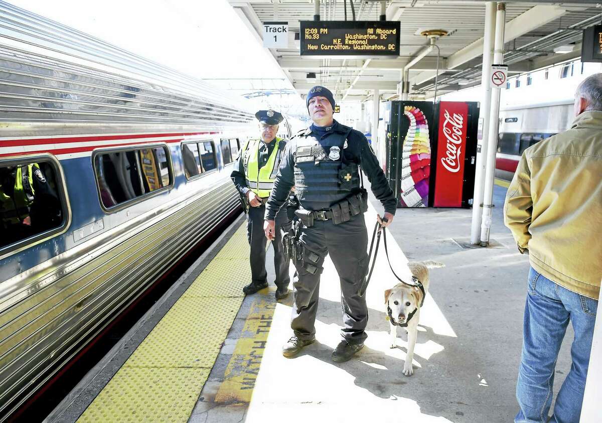 Amtrak Officer Larry Musso, left, and K-9 handler Joe Agnellino with explosives detection dog Roxy watch passengers board an Amtrak train heading to Washington, D.C., at Union Station in New Haven Tuesday.