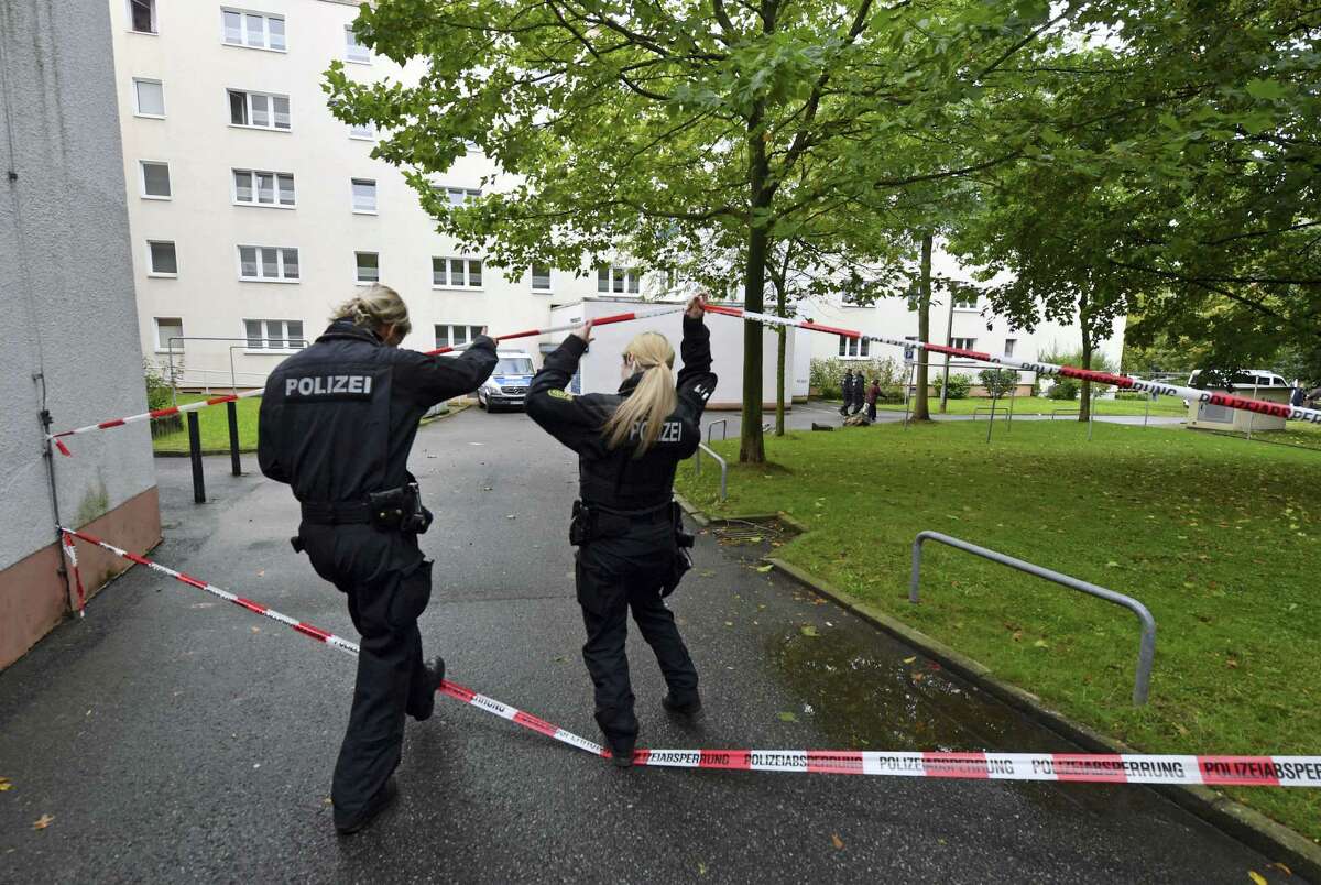 Two policewomen walk under a police cordon Oct. 9, 2016 that secures an apartment building in Chemnitz eastern Germany. German police search nationwide Sunday for a 22-year-old Syrian man believed to have been preparing a bombing attack, and were questioning a second Syrian man on suspicion he was involved in the plot.