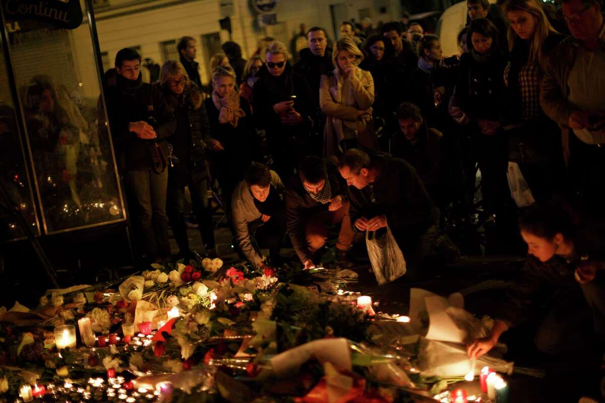 People light candles while paying their respect in front of The Belle Equipe restaurant in Paris, Saturday, Nov. 14, 2015, a day after the attacks on Paris. French President Francois Hollande vowed to attack Islamic State without mercy as the jihadist group admitted responsibility Saturday for orchestrating the deadliest attacks inflicted on France since World War II.