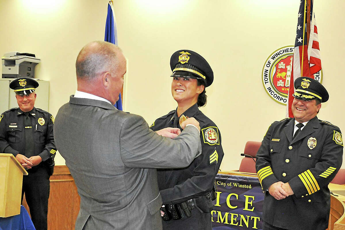 Winchester Police Chief William T. Fitzgerald Jr. proudly looks on as Sgt. Kim Boyne is pinned by her husband, New Milford Police Chief Shawn Boyne, during a ceremony in Winsted on Oct. 28.