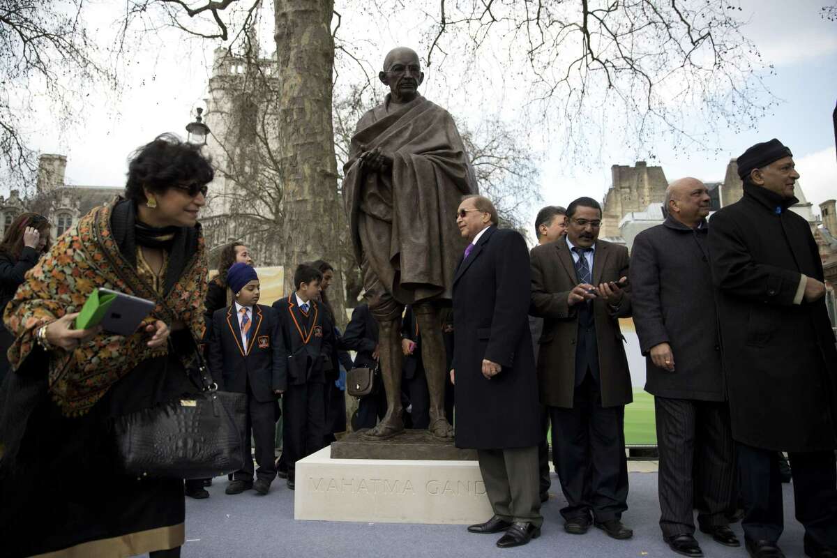 People stand around a new statue of Mahatma Gandhi by British sculptor Philip Jackson after it was unveiled in Parliament Square, London, Saturday, March 14, 2015. The bronze sculpture stands 9ft-high (2.75m) and will provide a focal point for commemorations of the 70th anniversary of Gandhi's death in 2018. (AP Photo/Matt Dunham)