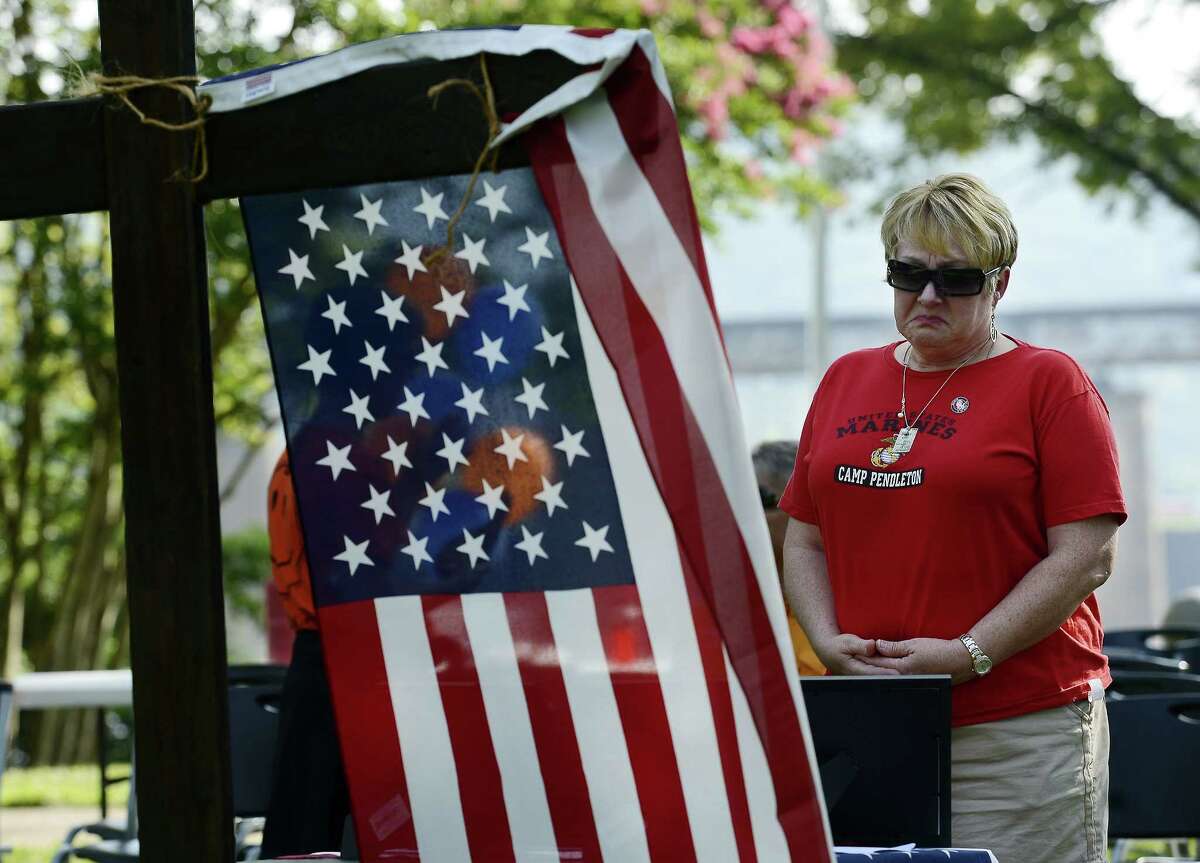 Dianna Varnes stands by a table adorned with photographs of the Marines who died after a memorial service at River Park Saturday in Chattanooga, Tenn. The U.S. Navy says a sailor who was shot in the attack on a military facility in Chattanooga has died, raising the death toll to five people.