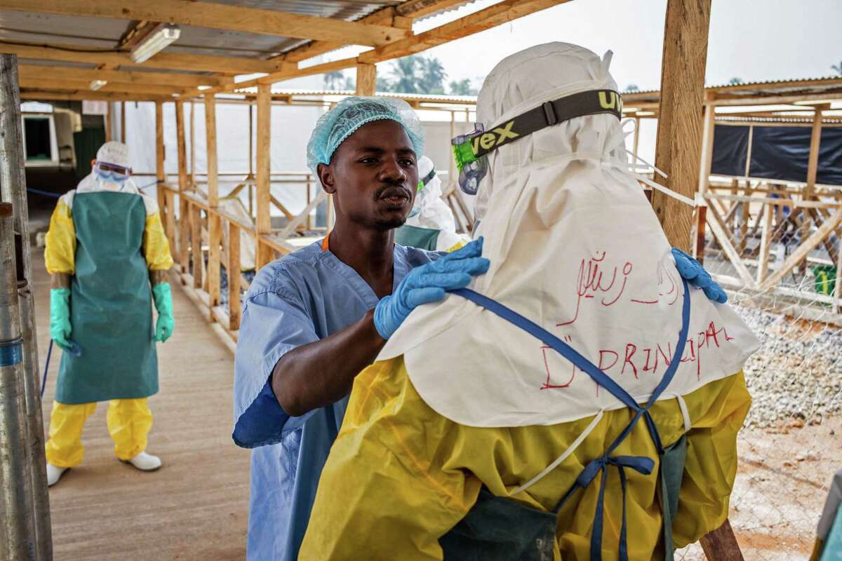 In this photo taken on Monday, March 2, 2015, a health care worker prepares a colleague's Ebola virus protective gear at an Ebola virus clinic operated by the International Medical Corps in Makeni, Sierra Leone. The World Health Organization says Thursday, March 12, 2015, its tally of Ebola deaths has passed the grim milestone of 10,000, mostly in West Africa. (AP Photo/ Michael Duff)