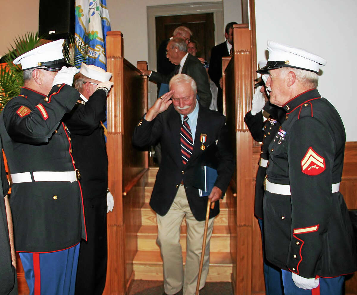 Dale Parsons-Marchione, an army veteran who served in Korea, is saluted as he steps down from the stage in the Founders Hall auditorium at Northwestern Connecticut Community College after a ceremony Thursday to honor veterans who participated in a book project with high school students.
