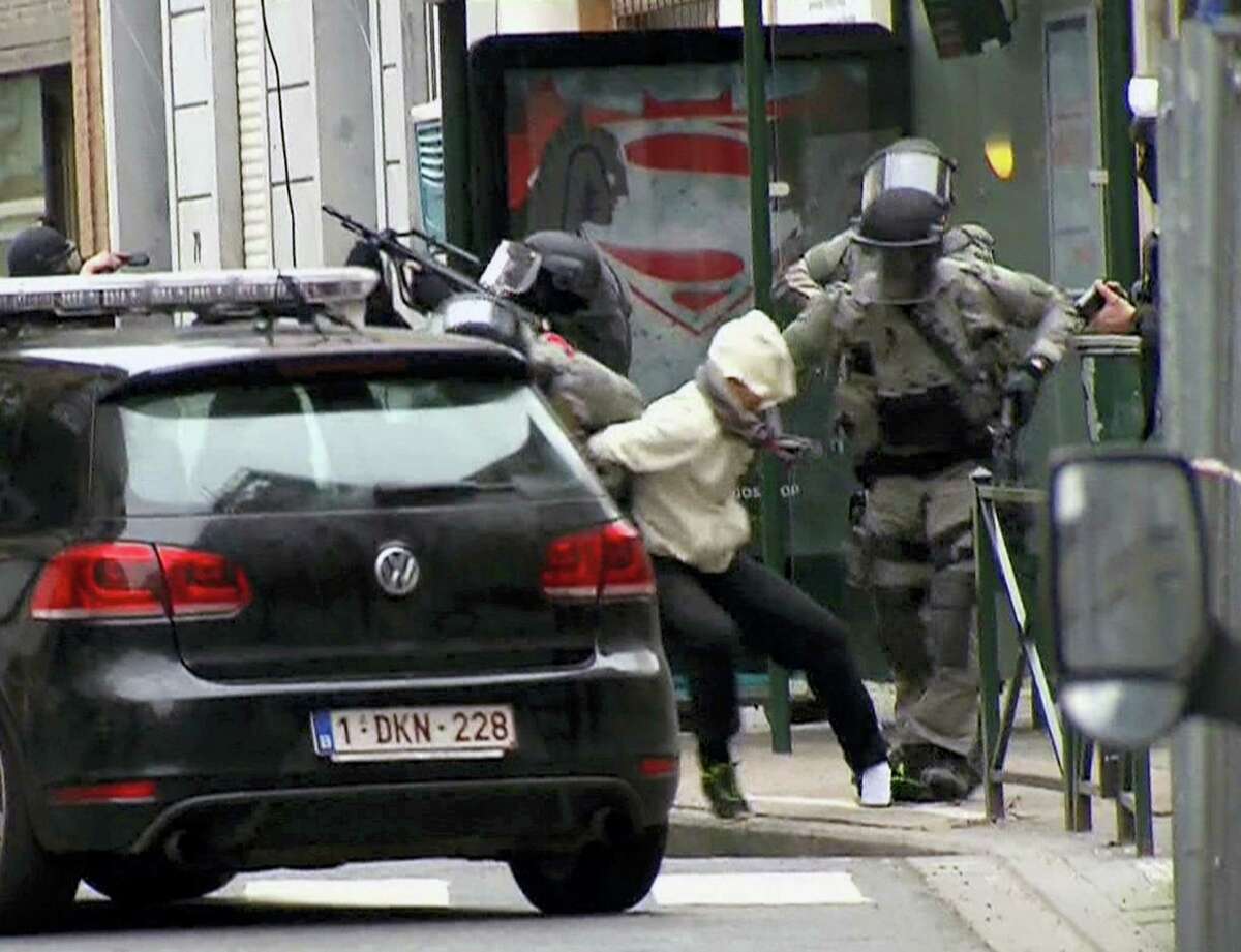 In this framegrab taken from VTM, something appears to drop from inside the trouser leg of Salah Abdeslam, centre, as he is arrested by police and bundled into a police vehicle during a raid in the Molenbeek neighborhood of Brussels, Belgium, Friday March 18, 2016. After an intense four-month manhunt across Europe and beyond, police on Friday captured Salah Abdeslam, the top suspect in last year’s deadly Paris attacks, in the same Brussels neighborhood where he grew up.