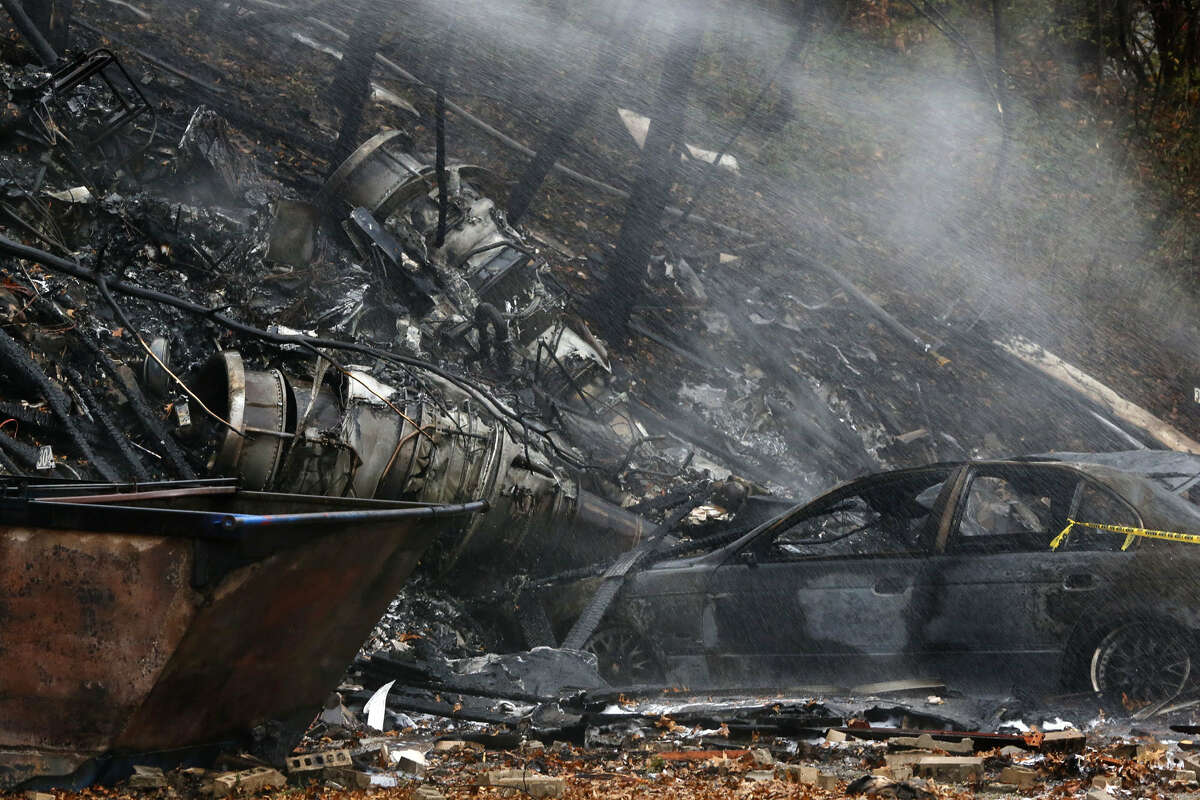 A charred car and aircraft debris smolder where authorities say a small business jet crashed into an apartment building in Akron, Ohio on Nov. 10, 2015.