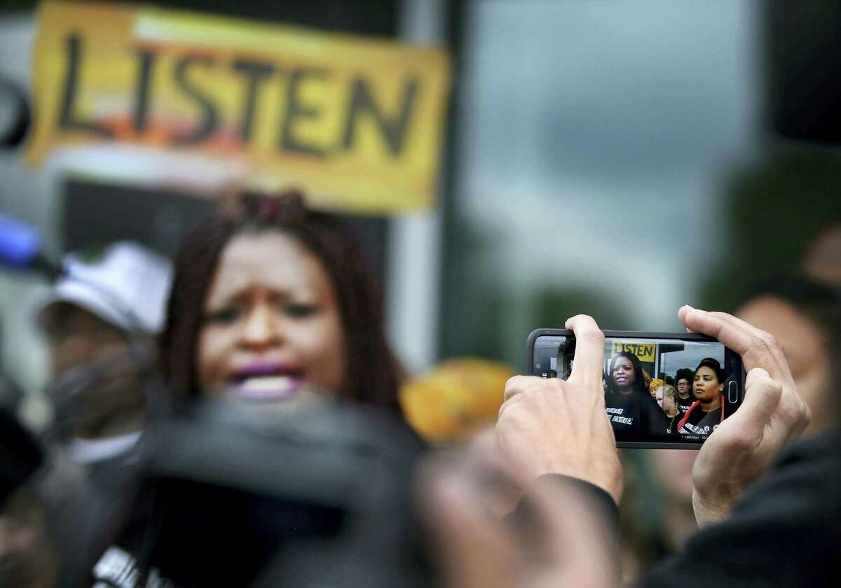 A member of the crowd takes a photo of Minneapolis NAACP President Nekima Levy-Pounds, center, as she speaks against police brutality during a press conference following U.S. Attorney Andrew Luger’s announcement that no criminal civil rights charges will be filed against two white Minneapolis police officers in the November shooting death of Jamar Clark, Wednesday, June 1, 2016, at the FBI local headquarters in Brooklyn Center, Minn.