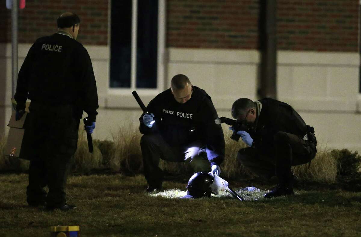 Police shine a light on and photograph a helmet as they investigate the scene where two police officers were shot outside the Ferguson Police Department on March 12, 2015, in Ferguson, Mo.