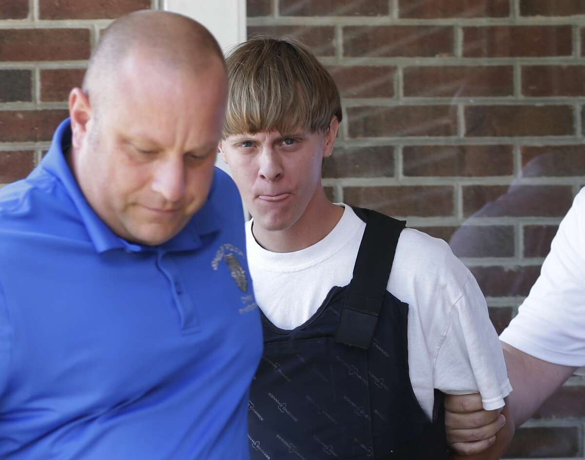 In this June 18, 2015 photo, Charleston, S.C., shooting suspect Dylann Storm Roof, center, is escorted from the Sheby Police Department in Shelby, N.C. He faces nine counts of murder, three counts of attempted murder and a weapons charge in the June 17 fatal shooting of nine black parishioners at Emanuel AME Church.