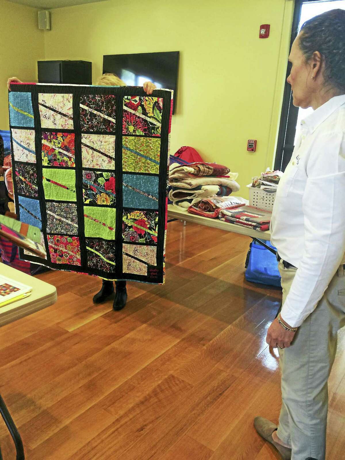 Noelia Ortiz - The Register CitizenQuilts That Care founder Deborah Van Steenbergen, right, admires a quilt made by members of her group during their recent meeting at the Litchfield Community Center.