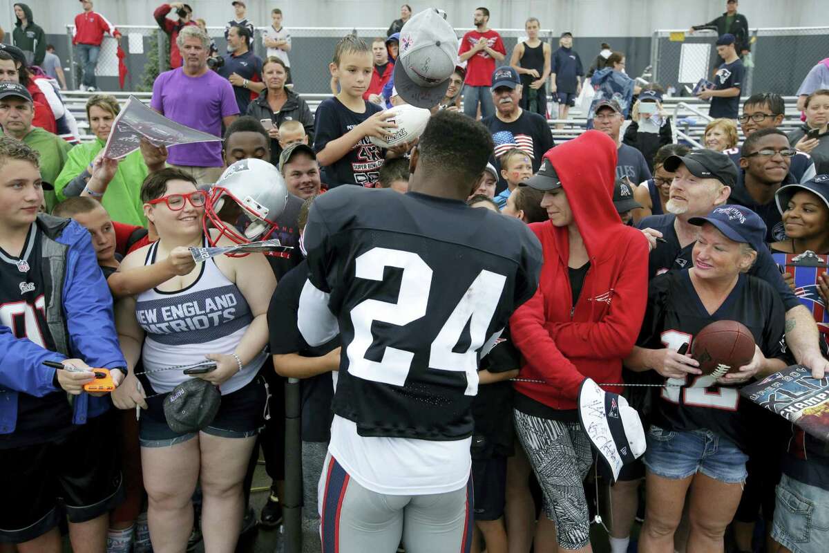 New England Patriots cornerback Cyrus Jones (24) signs autographs for fans following training camp practice Sunday in Foxborough, Mass.