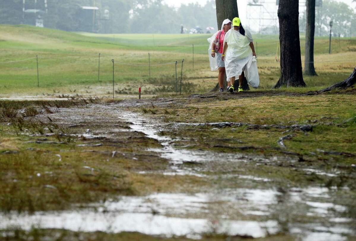 Women walk by the 18th hole after third round play was suspended for the day at the PGA Championship at Baltusrol Golf Club in Springfield, N.J., Saturday.