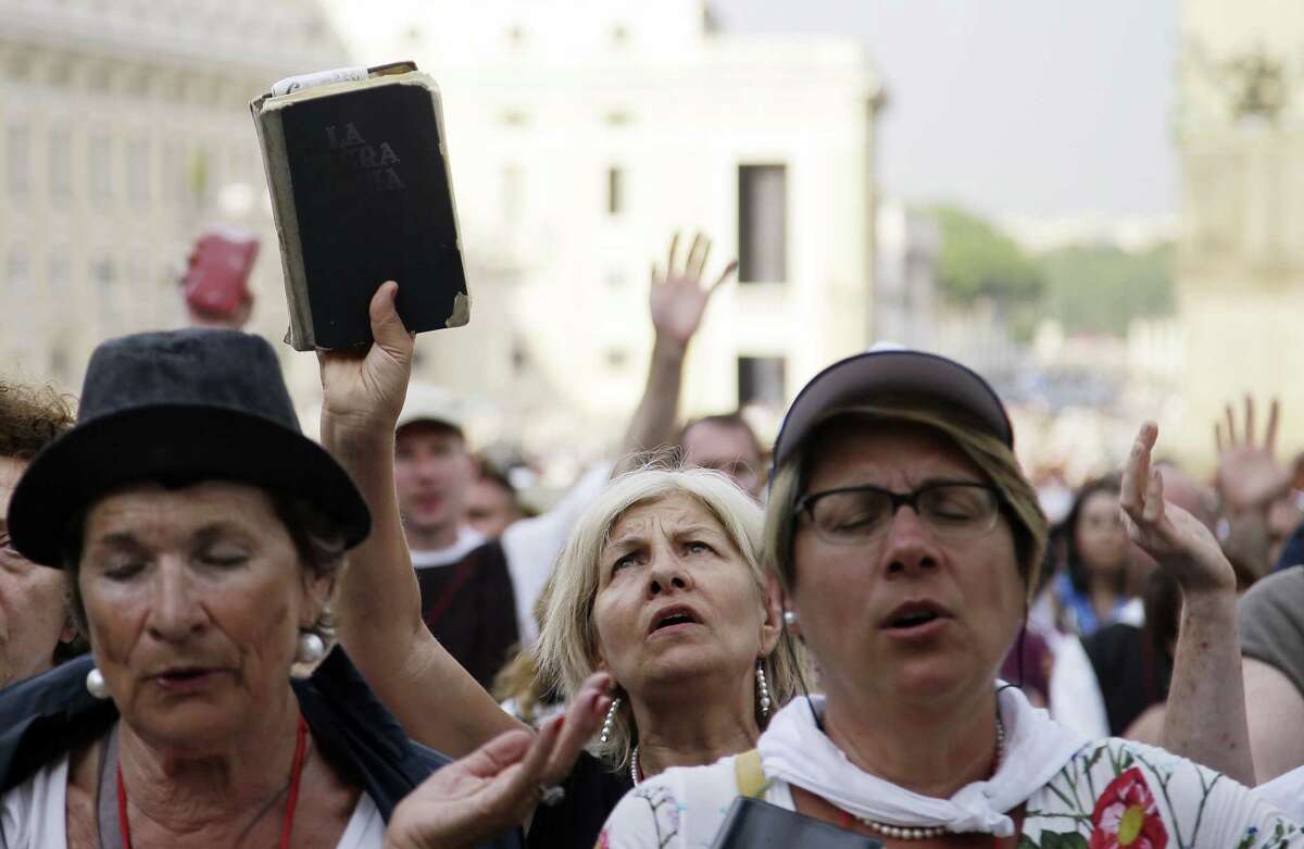 A woman holds up the Holy Bible as people crowd St. Peter's Square on the occasion of Pope Francis' meeting with faithful of the Holy Spirit movement at the Vatican, Friday, July 3, 2015. (AP Photo/Gregorio Borgia)