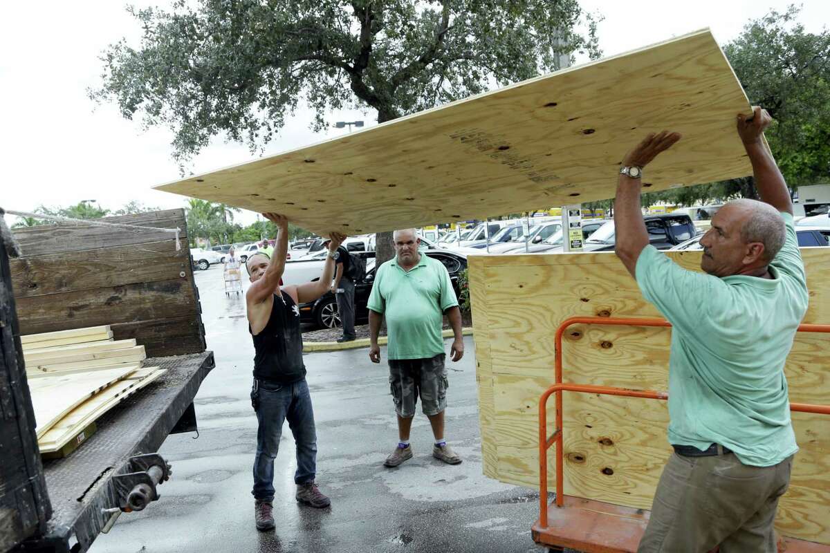 Jose Luis, left, and Miro Espana load plywood into a truck in preparation for Hurricane Matthew on Oct. 5, 2016 in Miami. People boarded up beach homes, schools closed, and officials ordered evacuations along the East Coast on Wednesday as Matthew tore through the Bahamas and took aim at Florida.