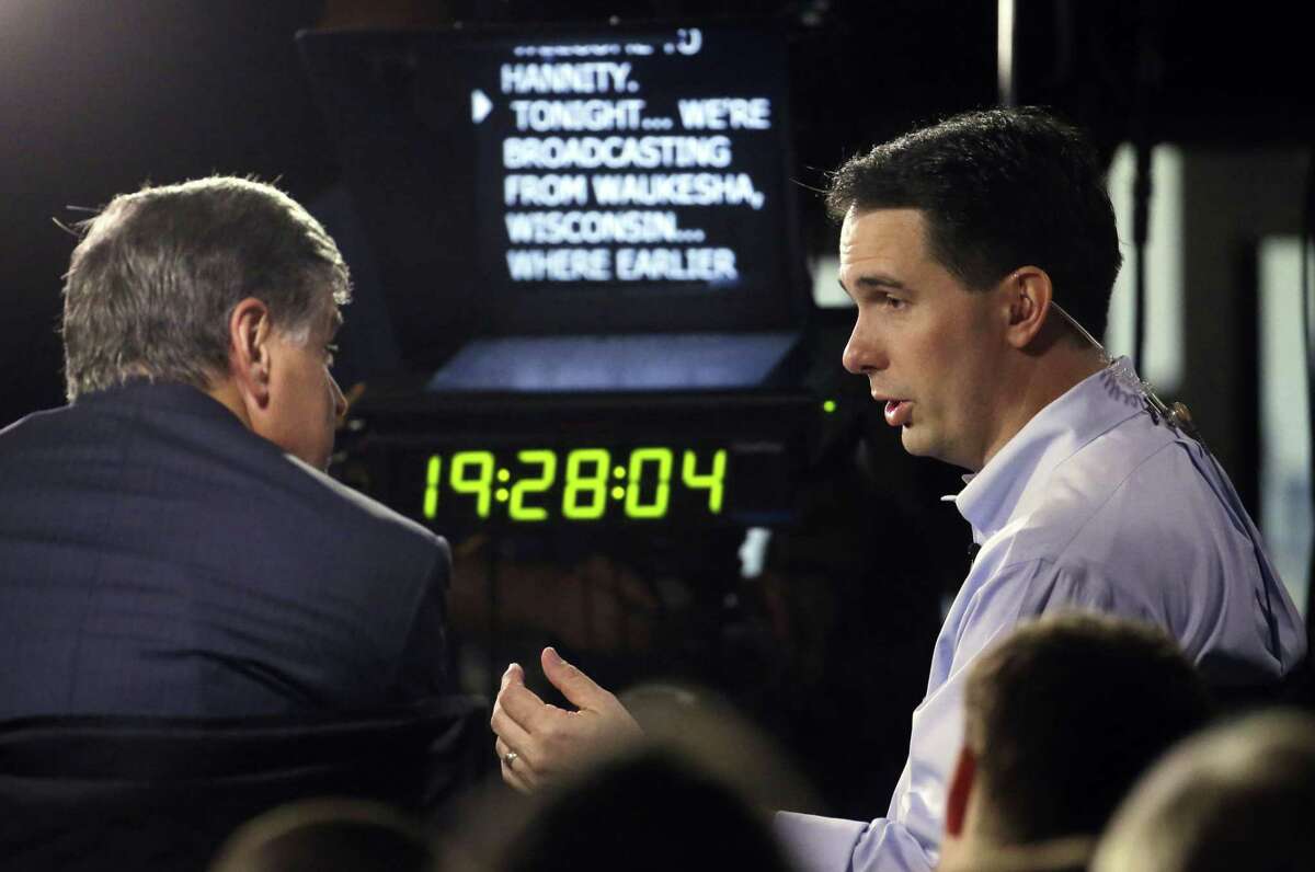 Wisconsin Gov. Scott Walker, right, gives a broadcast interview after announcing that he is running for the 2016 Republican presidential nomination at the Waukesha County Expo Center Monday in Waukesha, Wis.