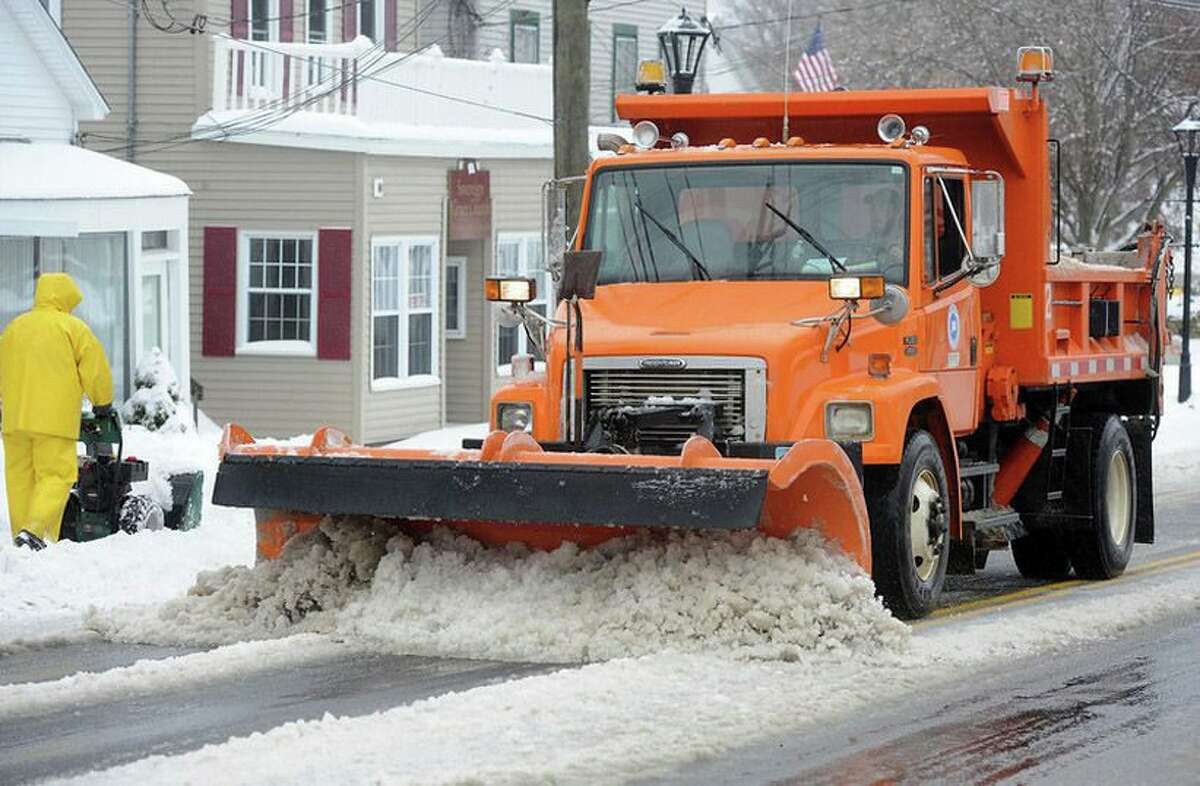A plow truck clears snow off the road.