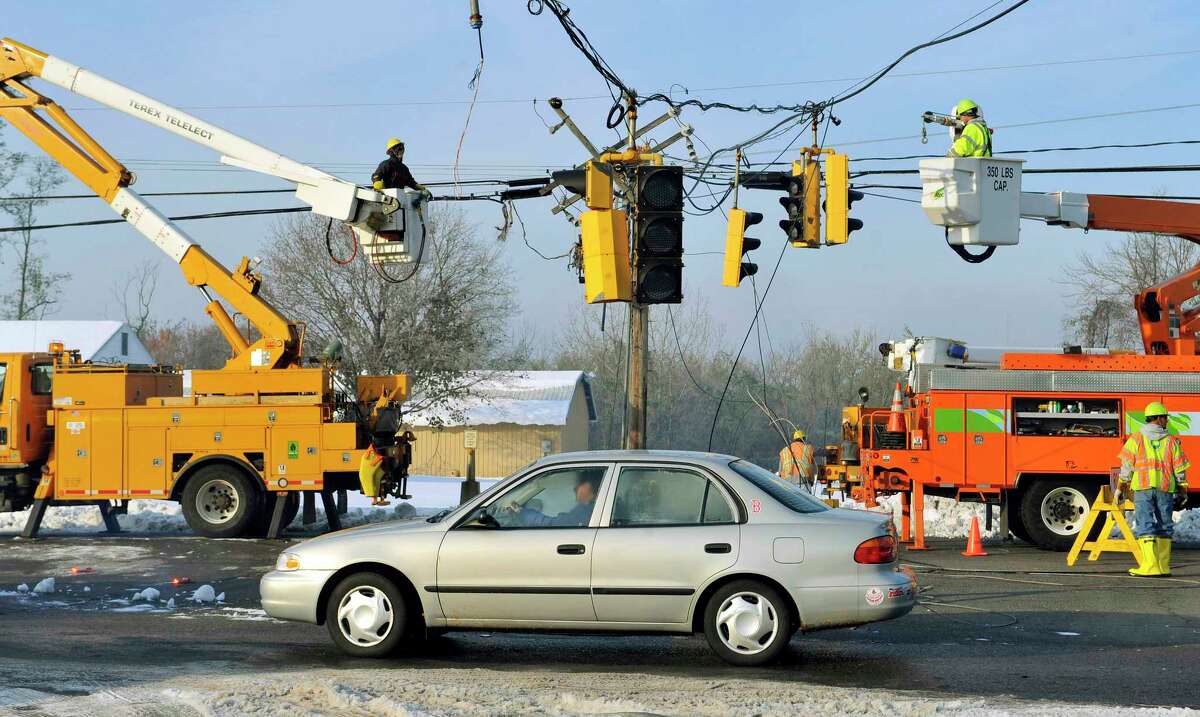 In this Oct. 31, 2011 photo, a vehicle passes under a traffic light damaged by a storm as department of transportation and power workers repair downed lines on Route 5 in South Windsor, Conn. The state’s largest electrical utility collaborated with the University of Connecticut to open the Eversource Energy Center at UConn in October 2015, devoted to studying ways to better predict and prepare the state’s power infrastructure for natural disasters.