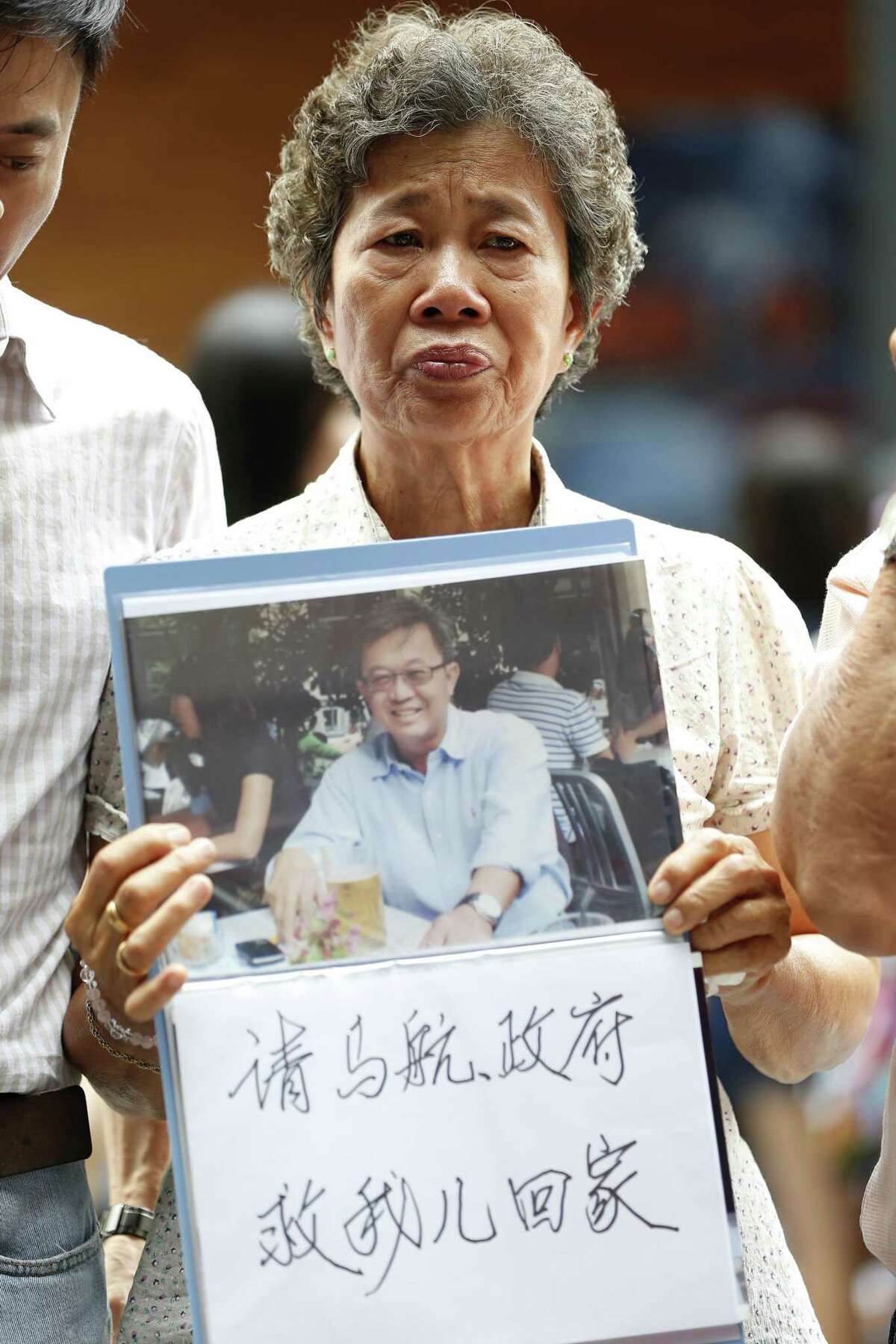 Malaysia’s Madam Wong holds a message and a photo of her son, Tan Chong Ling, who was a passenger on board the ill fated Malaysia Airlines Flight 370, during a remembrance event in a mall outside Kuala Lumpur, Malaysia Sunday.
