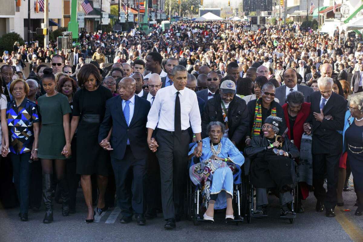 President Barack Obama, center, walks as he holds hands with Amelia Boynton, who was beaten during “Bloody Sunday,” as they and the first family and others including Rep. John Lewis, D-Ga,, left of Obama, walk across the Edmund Pettus Bridge in Selma, Ala. for the 50th anniversary of “Bloody Sunday,” a landmark event of the civil rights movement Saturday. From front left are Marian Robinson, Sasha Obama and first lady Michelle Obama.