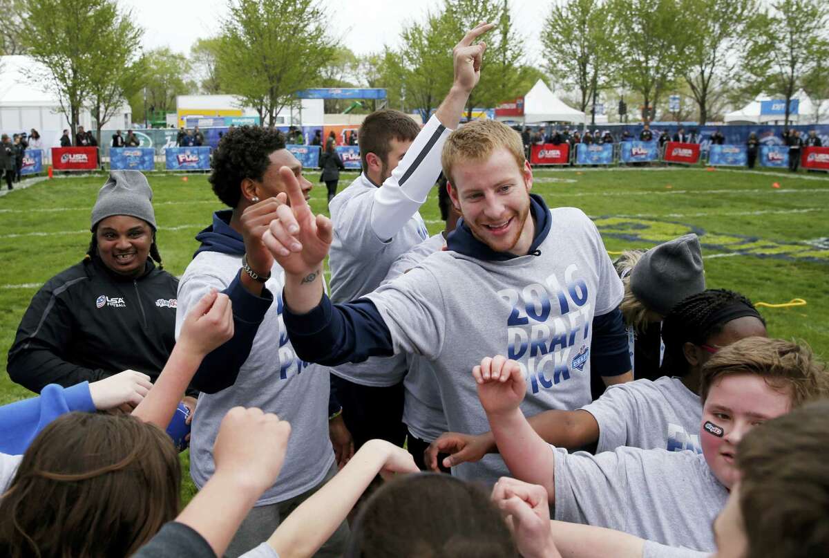 North Dakota State’s Carson Wentz huddles with children during an NFL Play 60 event at Grant Park Wednesday in Chicago before today’s first round of the NFL football draft.