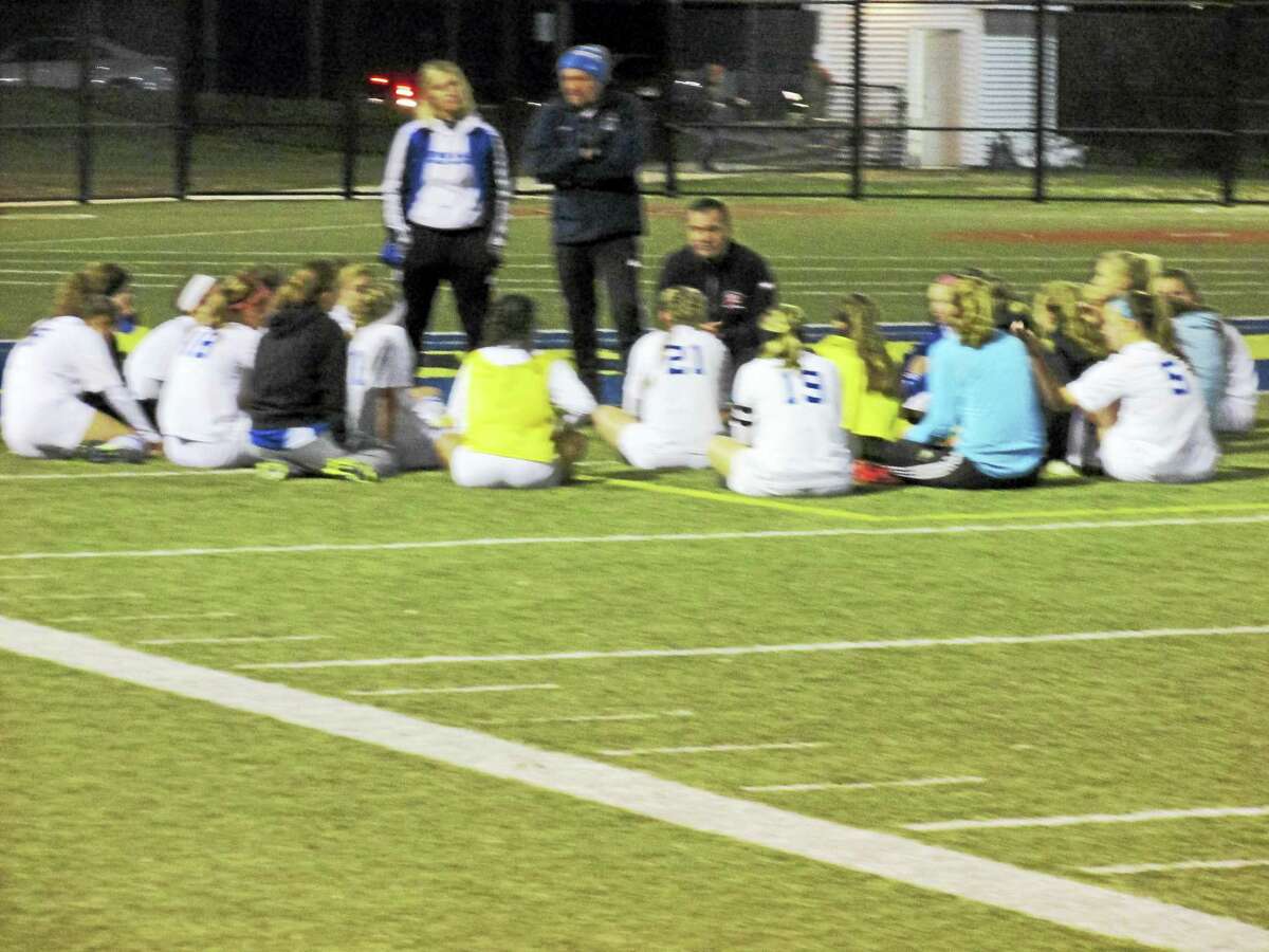 Lewis Mills coach Dave Francalangia (kneeling) talks strategy for an even second half in a Class M girls soccer semifinal loss to Immaculate Monday night at Waterbury’s Municipal Stadium.