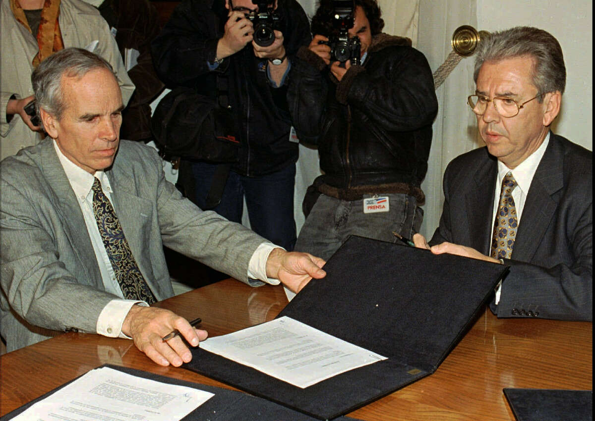 In this July 7, 1997, file photo, American millionaire Douglas Tompkins, left, and Juan Villarzu, chief of staff of the Chilean president, hold the text of an accord signed in Santiago, Chile. Officials in Chile said Tuesday, Dec. 8, 2015, that the wealthy U.S. businessman and environmental activist has died from severe hypothermia in a kayaking accident.