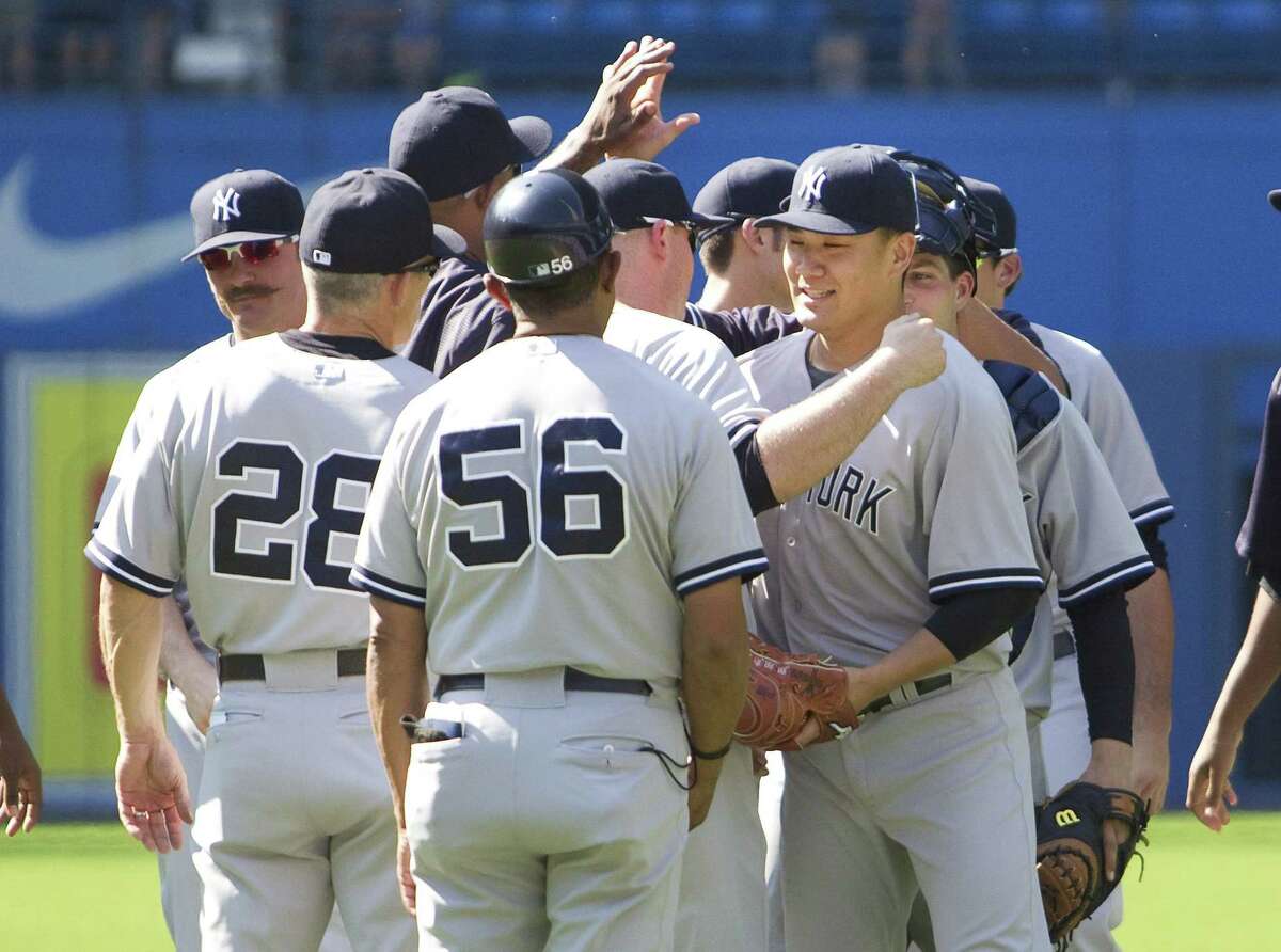 Yankees’ starting pitcher Masahiro Tanaka is congratulated by teammates after beating the Blue Jays on Saturday.