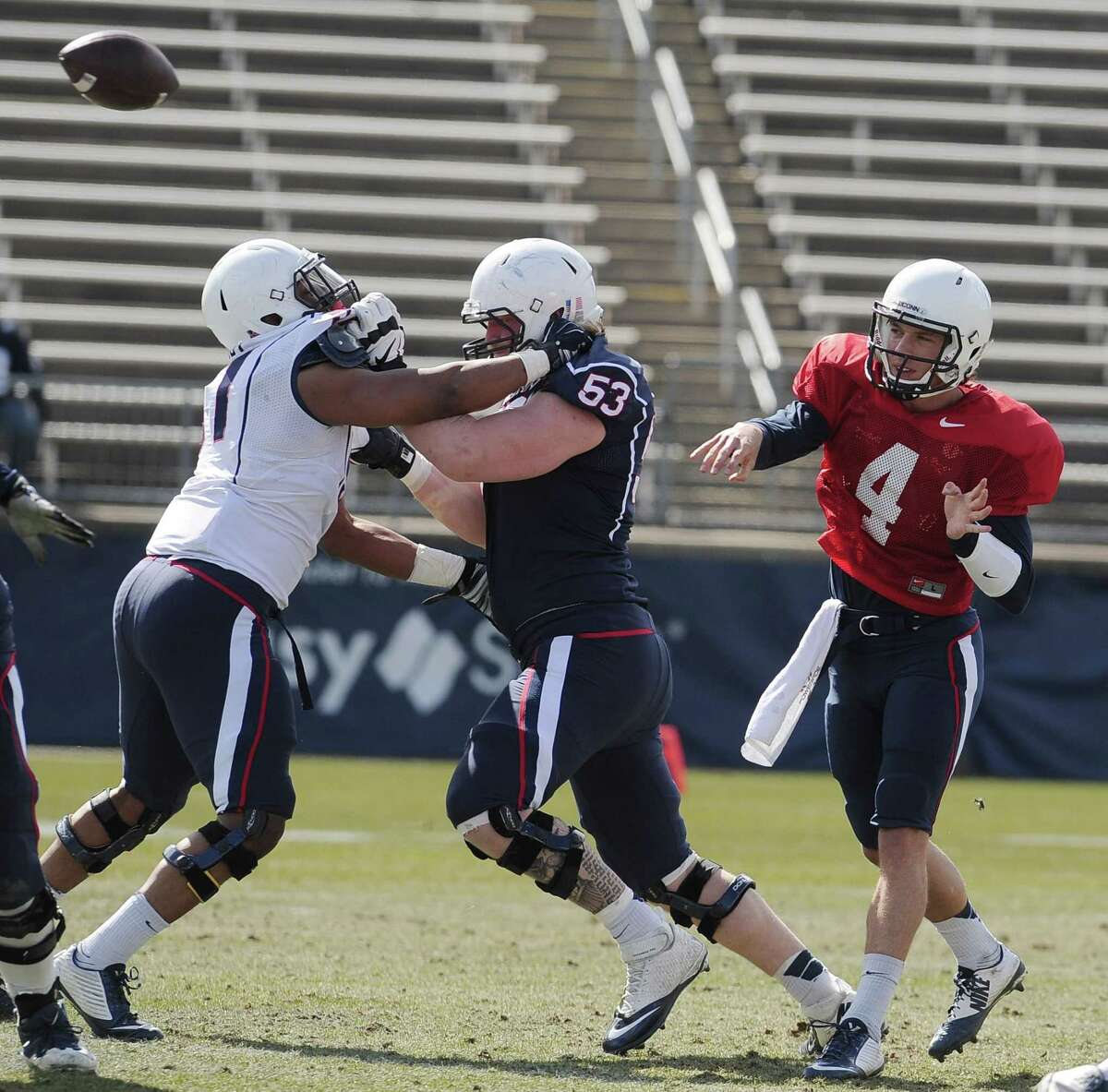 UConn quarterback Bryant Shirreffs throws over White’s Omaine Stephens, left, and Blue’s Andres Knappe during the first half of the annual Blue-White spring game on Saturday at Rentschler Field.