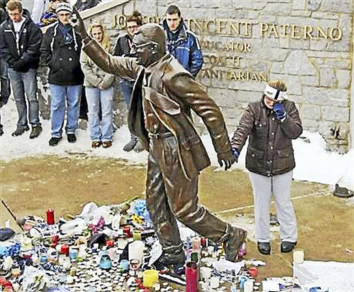 In this Jan. 22, 2012, file photo, a woman pays her respects at a statue of former Penn State football coach Joe Paterno outside Beaver Stadium on the Penn State University campus in State College, Pa. More than 200 former Penn State football players are petitioning university leaders to return the bronze statue of Paterno that stood outside the school’s football stadium. The statue of the late football coach was removed in 2012. The players sent a letter Tuesday, July 5, 2016, to the board of trustees and Penn State President Eric Barron calling for the statue’s return.