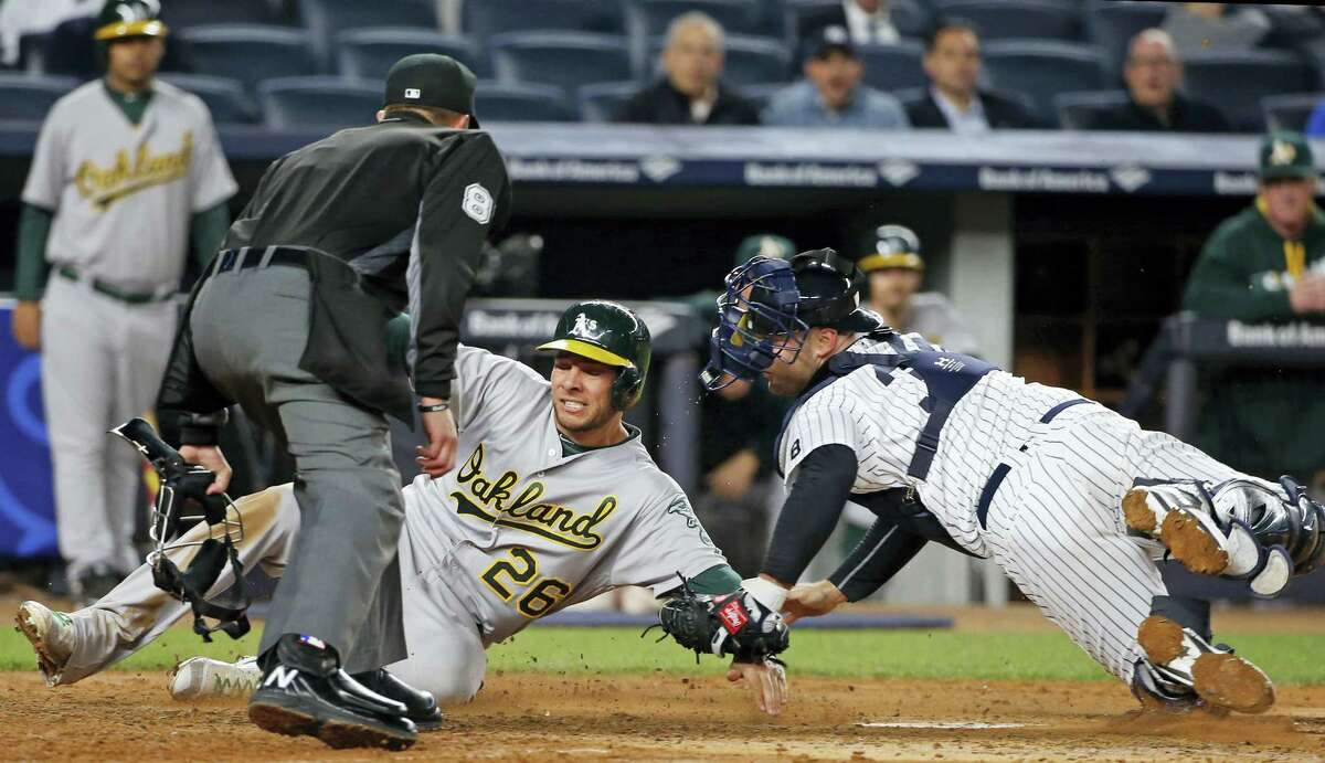 Home plate umpire Jeff Kellogg watches as the Athletics’ Danny Valencia (26) is tagged out at the plate by Yankees catcher Brian McCann on Wednesday.