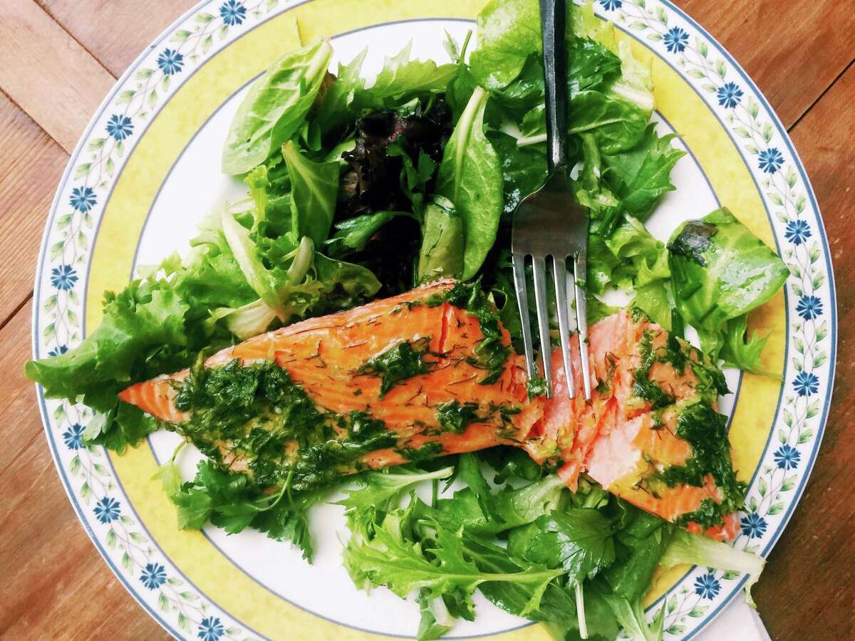 This warm-weather recipe combines salmon bathed in olive oil and herbs with spring-y greens and salad. It’s the kind of lighter, brighter meal we tend to want during summer.