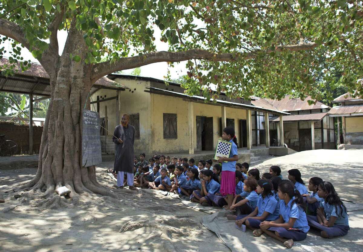 Indian school children attend a class under a tree outside a school in east Gagolmari village about 70 kilometers (44 miles) east of Gauhati, India, Thursday, April 9, 2015. According to the UNESCO Education for All Global Monitoring Report 2015, only half of all countries have achieved the most watched goal of universal primary enrollment. The report launched Thursday says, India has reduced its out of school children by over 90% Since 2000.