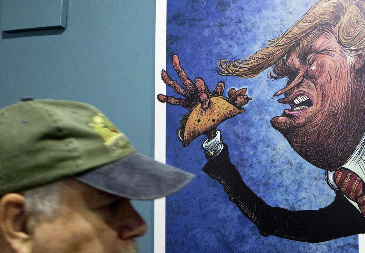 An American visitor walks past a cartoon of a Mexican wrapped in a taco sticking his tongue out at a depiction of President-elect Donald Trump, in an exhibition titled; “Trump: A wall of caricatures,” at the Caricature Museum in downtown Mexico City, Thursday, Nov. 10, 2016. The exhibition, which features dozens of works by Mexican and international cartoonists, mocks amongst other things Trump’s derogatory statements about Mexicans and his plans to build a wall between the two countries.(AP Photo/Rebecca Blackwell)