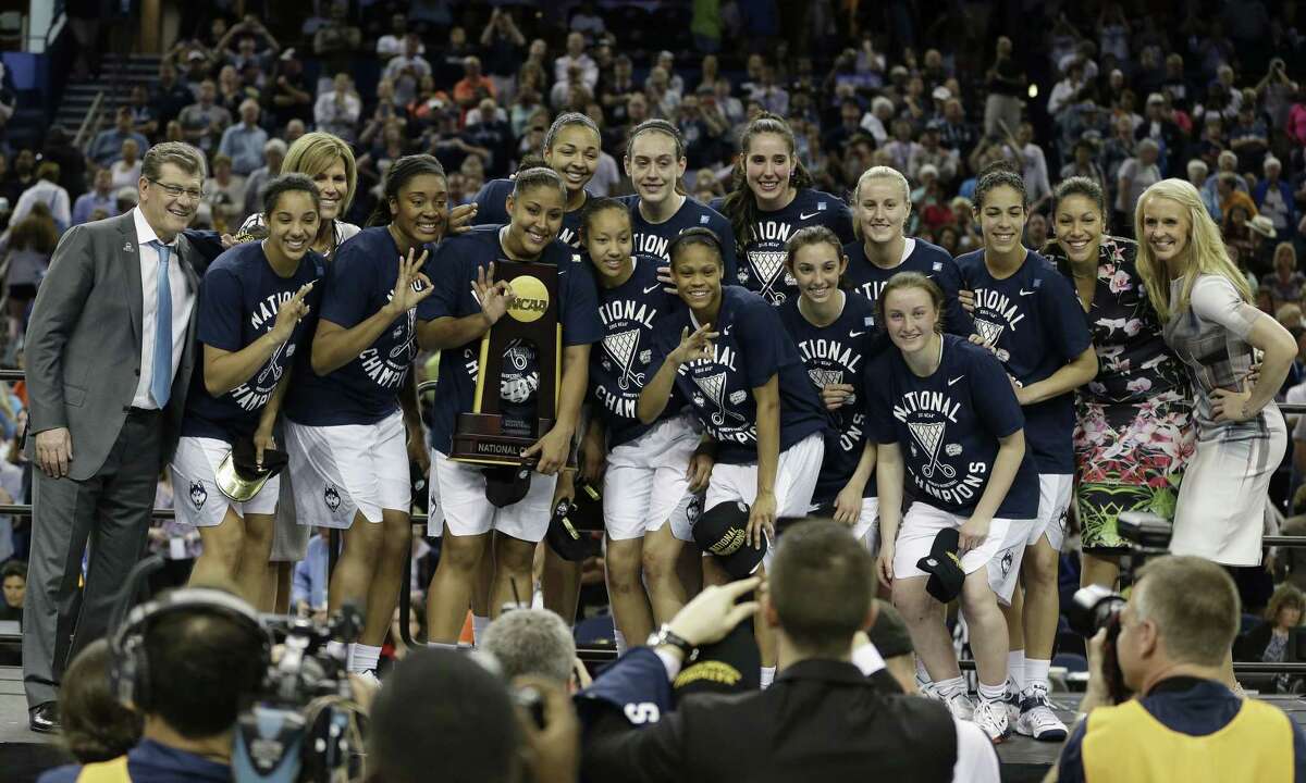 UConn players and coaches pose for photos after winning the national championship against Notre Dame on Tuesday in Tampa, Fla.