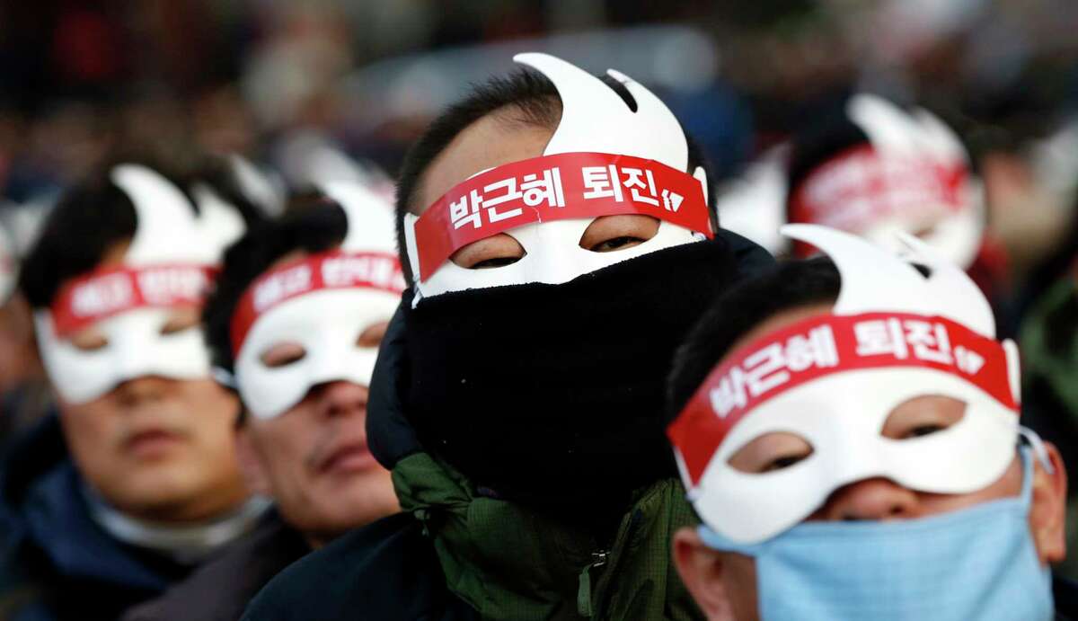 South Korean protesters attend an anti-government rally in downtown Seoul, South Korea, Saturday, Dec. 5, 2015. Wearing white half-masks and carrying flowers and banners, thousands of South Koreans marched in Seoul on Saturday against conservative President Park Geun-hye, who had compared masked protesters to terrorists after clashes with police broke out at a rally last month.