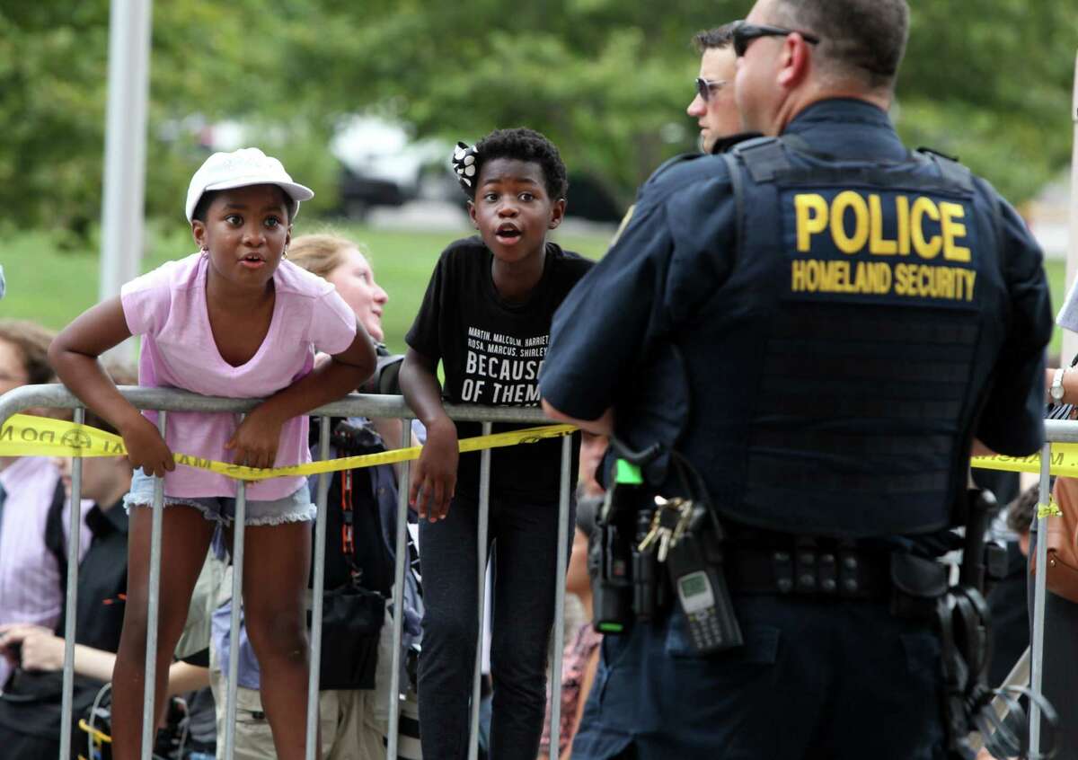 McKenzie Davis, left, and Alice Dowd, chant at an officer as a crowd of protesters gathers as officers stand watch Monday, Aug. 10, 2015, in St. Louis. Protesters have been arrested after blocking the entrance to the St. Louis federal courthouse while calling for more aggressive U.S. government response to what they call racist law enforcement practices.