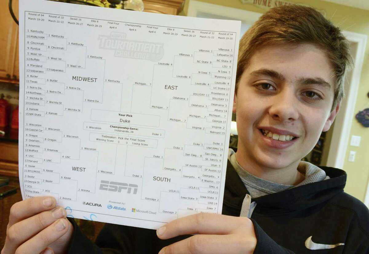Sam Holtz, a sixth-grader from Hawthorn Woods, Ill., poses at home Tuesday with his near-perfect ESPN NCAA men’s basketball bracket where he picked Duke to defeat Wisconsin in the final. ESPN officials told Holtz he is ineligible to claim the top prize — a $20,000 gift card — because he’s 12 years old.
