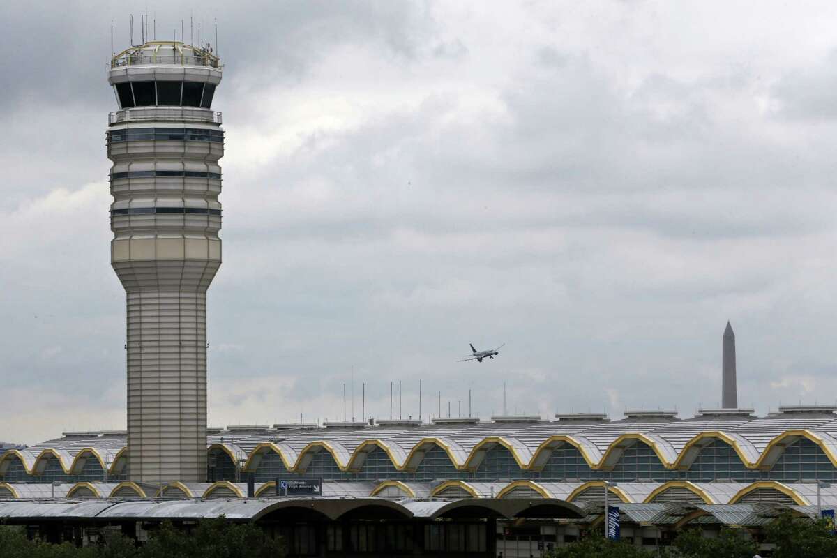 An airplane flies between the air traffic control tower and the Washington Monument at Washington’s Ronald Reagan National Airport, Aug. 10, 2015. For more than three years, the government has kept secret a study it requested that found air traffic controllers’ work schedules often lead to chronic fatigue, making them less alert and endangering the safety of the national air traffic system, according to report on the study obtained by The Associated Press.