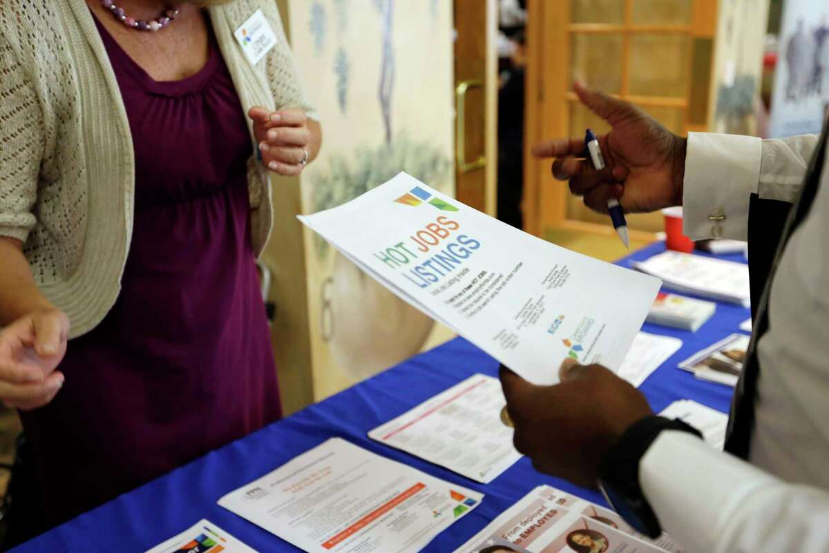 In this Tuesday, Oct. 6, 2015, photo, military veteran Mark Cannon, of Miami, right, talks with Cynthia Carcillo, left, a veterans outreach representative for Career Source Broward, about employment opportunities at a job fair for veterans, in Pembroke Pines, Fla. The number of people seeking U.S. unemployment aid dropped sharply a week earlier, the Labor Department said Wednesday, Nov. 25, 2015, the latest sign that businesses are cutting few jobs.