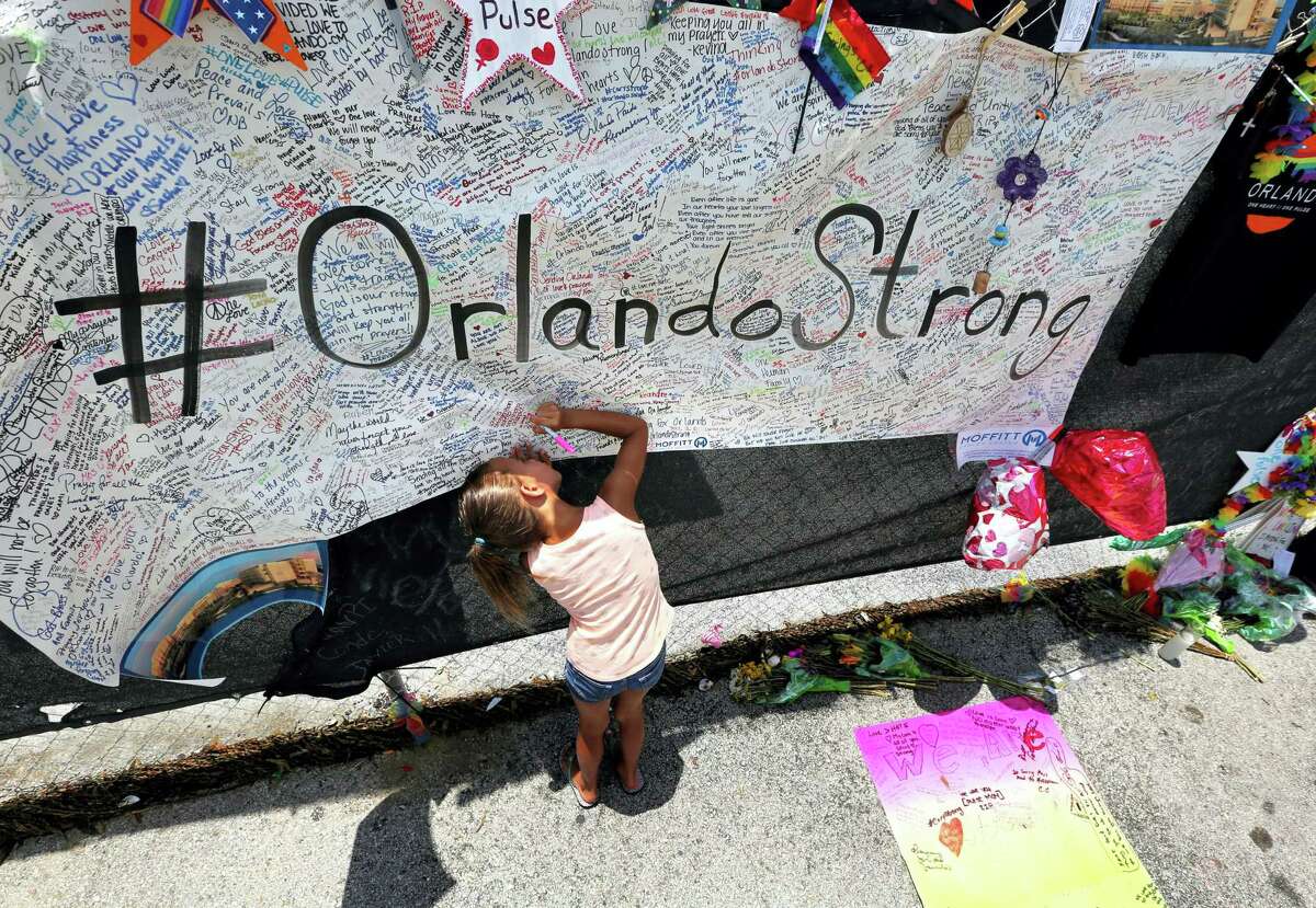 Seven-year-old Kyndall Whitley signed a poster Wednesday as visitors continued to flock to the roadside memorial at the Pulse nightclub in Orlando, Florida.