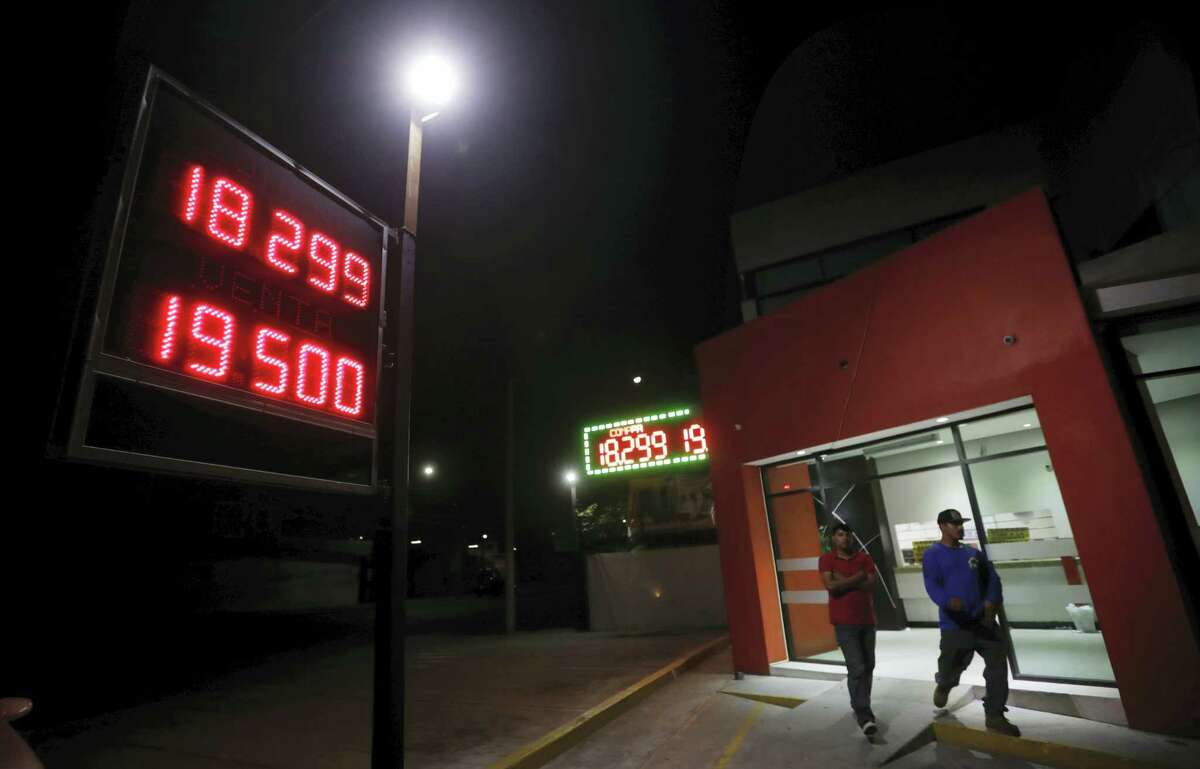 Men leave a currency exchange business displaying rates of the Mexican peso Tuesday, Nov. 8, 2016 in Tijuana, Mexico. The rising prospect of a Trump presidency jolted markets around the world Wednesday, sending Dow futures and Asian stock prices sharply lower as investors panicked over uncertainties on trade, immigration and geopolitical tensions. The Mexican peso likewise tumbled and investors looking for safe assets bid up the price of gold.