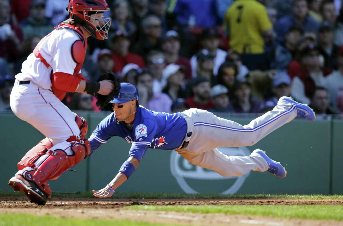 The Blue Jays’ Ryan Goins, right, scores as Red Sox catcher Ryan Hanigan, left, waits for the ball in the seventh inning on Sunday.