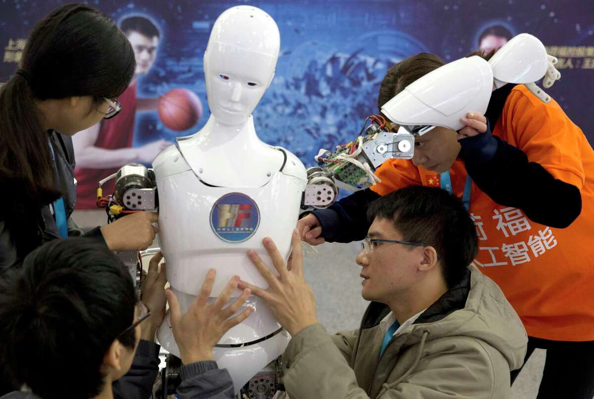 Chinese students work on the Ares, a humanoid bipedal robot designed by them with fundings from a Shanghai investment company, displayed during the World Robot Conference, which was held in Beijing earlier this summer.