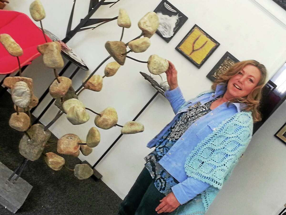 Karen Rossi shows off a work of art, intended to be a modern take on traditional stone cairns, placed in a neighborís gallery.