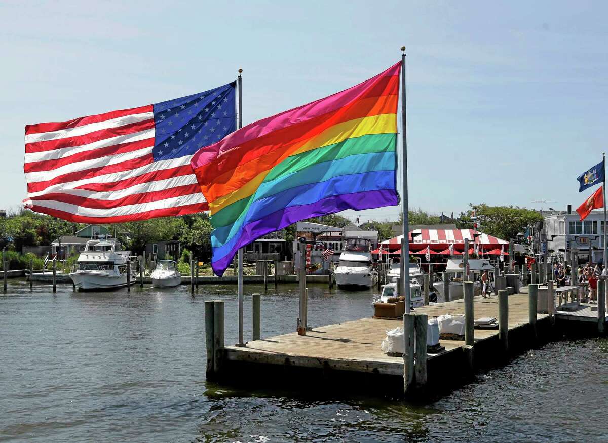 In this June 23, 2013, photo, an American flag and a LGBT Rainbow flag are displayed on the ferry dock in the Fire Island community of Cherry Grove, N.Y.