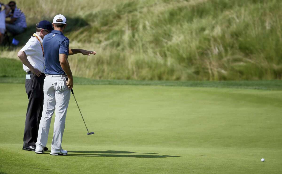 In this June 19, 2016 photo, Dustin Johnson, right, talks to a rules official on the fifth green during the final round of the U.S. Open golf tournament at Oakmont Country Club in Oakmont, Pa. Top rules experts from around the world have been meeting privately the last five years to simplify the rules in what could be the most expansive rules overhaul ever.