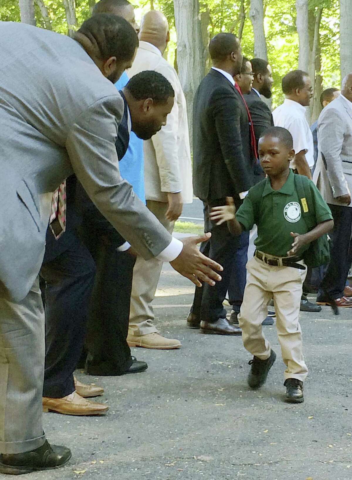In this Aug. 30, 2016 photo, black professional men from the community greet students arriving for the first day of school at Martin Luther King Jr. Elementary School in Hartford, Conn. Similar welcome ceremonies have been staged for students from minority communities in cities around the country including Atlanta, Boston and Seattle.