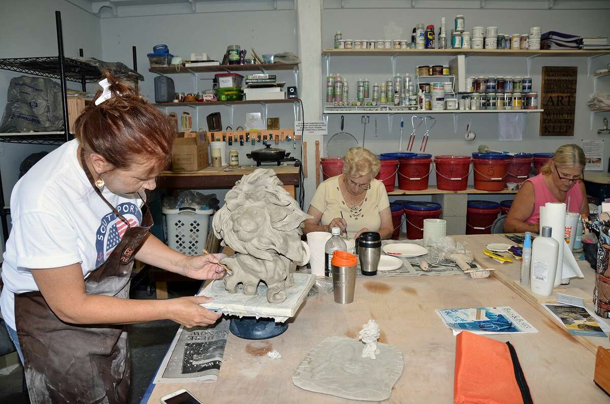 Pat Jasinnas, left, owner of the Earth to Fire pottery studio and retail store in Southport, N.C., works on her lion while two of her Monday gang work on their projects.