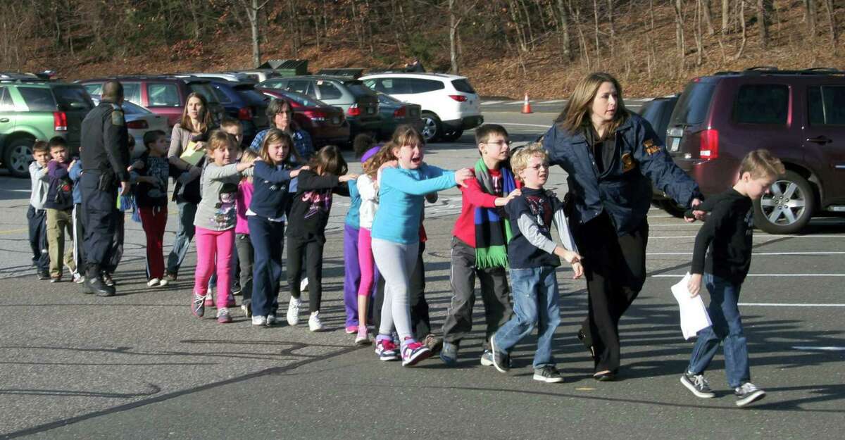 In this photo provided by the Newtown Bee, Connecticut State Police lead a line of children from the Sandy Hook Elementary School in Newtown Friday, Dec. 14, 2012 after a shooting at the school. Recordings of 911 calls from the Newtown school shooting are being released Wednesday Dec. 4, 2013, days after a state prosecutor dropped his fight to continue withholding them, despite an order to provide them to The Associated Press.