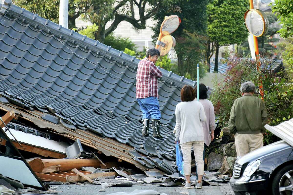 Residents look for an access to their home on the road which is blocked by a collapsed house, in Mashiki, Kumamoto prefecture, southern Japan Saturday, April 16, 2016. A major quake shook southwestern Japan, barely a day after another quake hit the same region.